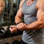 A muscular man in a gym, flexing his wrists and showing full range of motion without pain